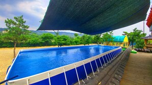 Piscina rectangular con interior azul, rodeada por una terraza de madera y una valla de seguridad blanca.