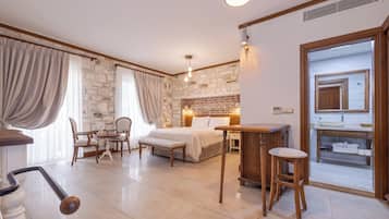 A bedroom with a bed, bedside table, and a small sitting area with a chair and table.