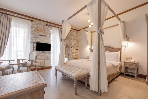 Um quarto com lareira de pedra, cama com dossel, mesa de cabeceira e um banco de madeira.