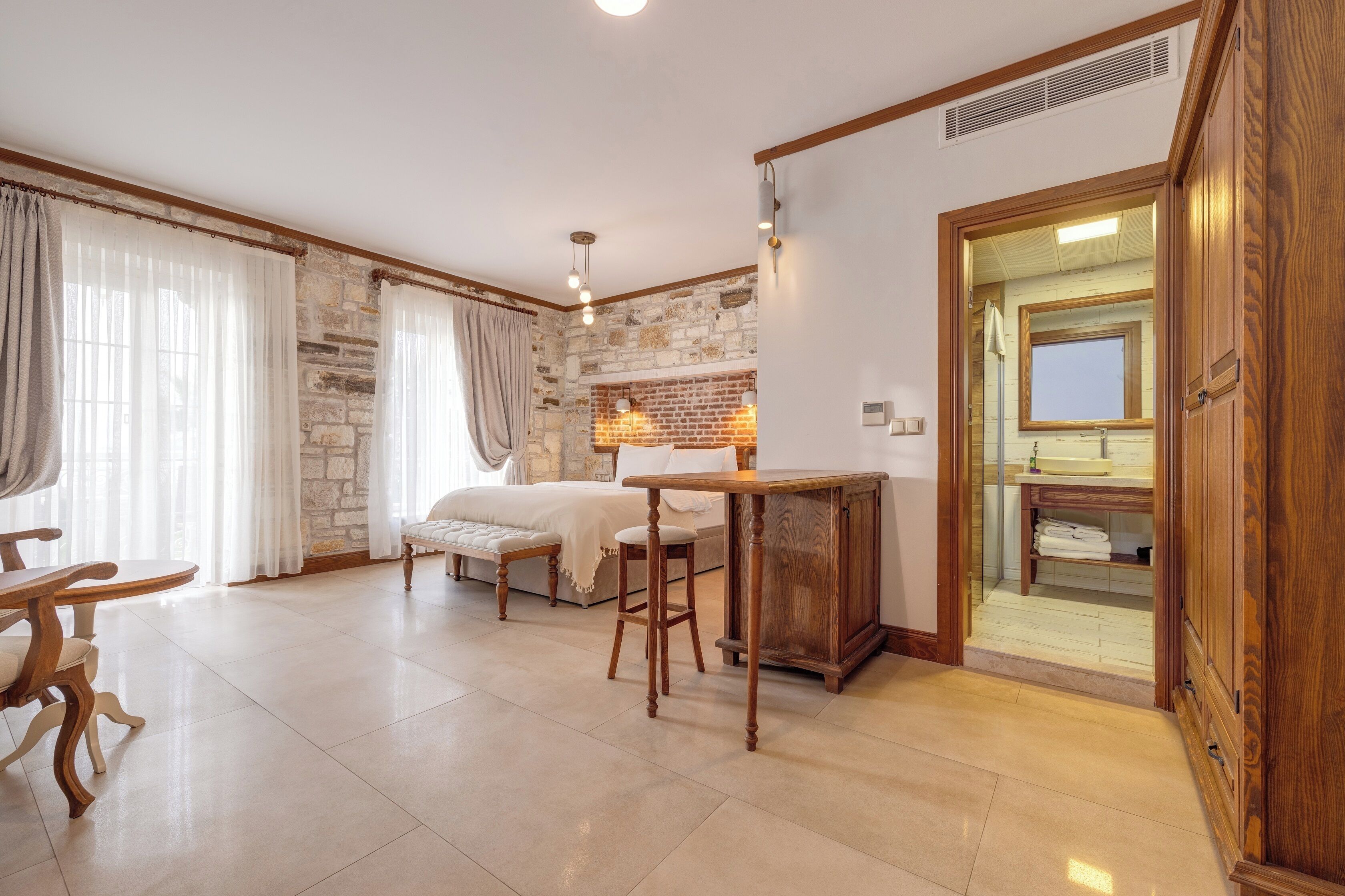 Una habitación acogedora con cama, una mesa de madera, una zona de bar y un baño visible a través de una puerta abierta.