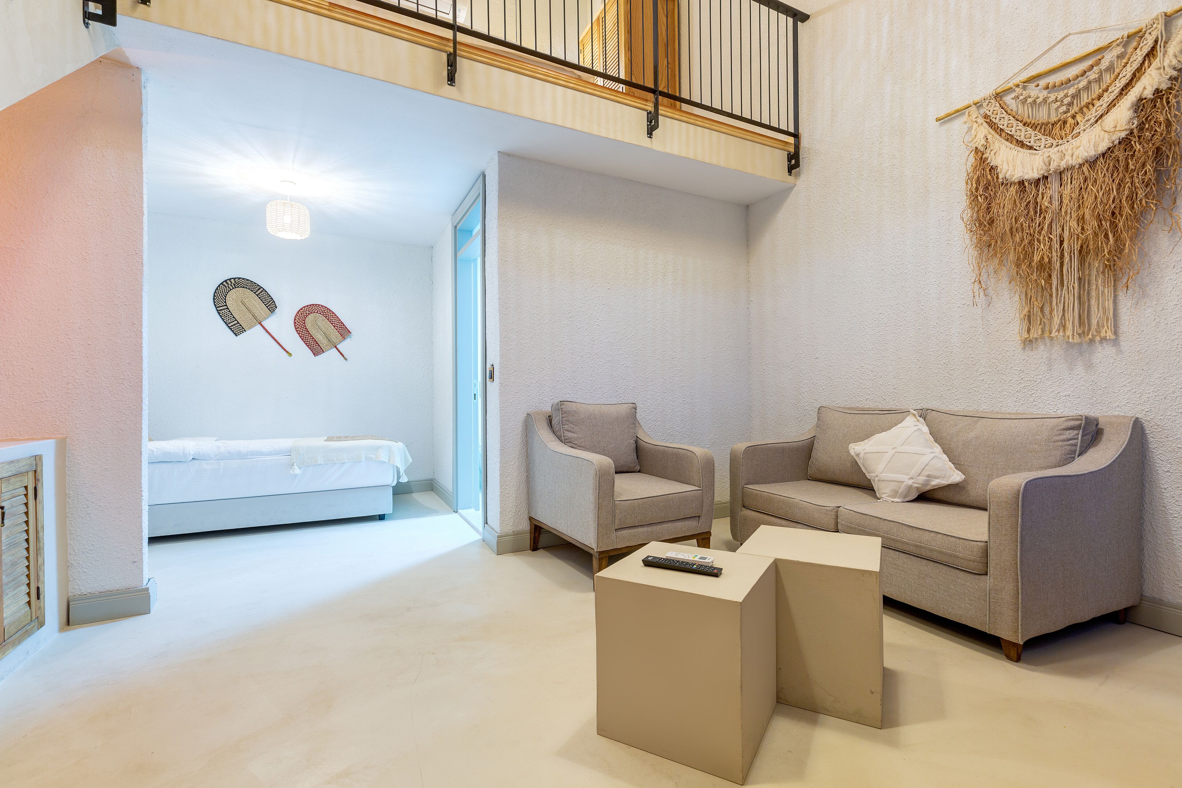A modern living room with a sofa set, a coffee table, and a bed in the background.