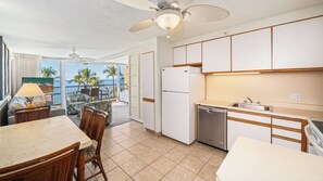 Una cocina compacta equipada con refrigerador, lavavajillas y una zona de comedor con sillas y mesa.