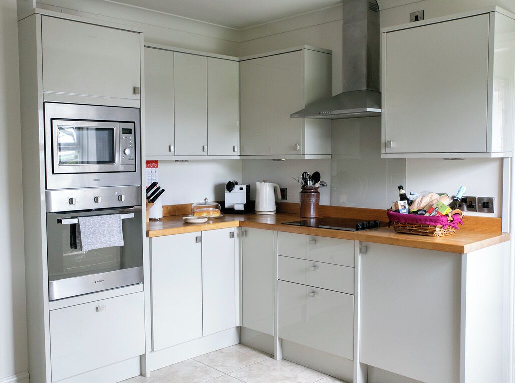 Een moderne keuken met witte kastjes, een roestvrijstalen oven, een magnetron en een houten aanrecht.
