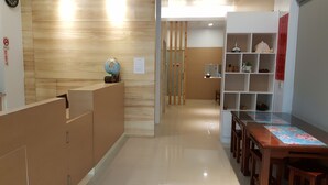Un espace d’accueil comprenant un comptoir de réception en bois, un globe terrestre et un panneau d’affichage.