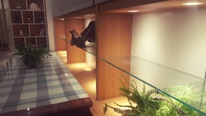 Un hall d’entrée moderne avec un sol à carreaux, des lambris en bois, une rambarde en verre et une plante en pot.