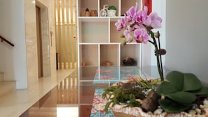 Un intérieur moderne avec un escalier en bois, un tapis à motifs floraux et une plante en pot.