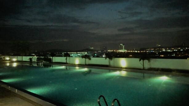 A swimming pool at night with city lights in the background. - Cozy Crib at 7 Tree Seven Residence (Cheras)