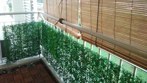 A balcony with a view of a garden, a metal railing, and a window with blinds. - Cozy Crib at 7 Tree Seven Residence (Cheras)