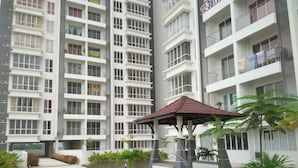 A multi-story residential building with balconies, a covered outdoor seating area, and a well-maintained lawn. - Cozy Crib at 7 Tree Seven Residence (Cheras)