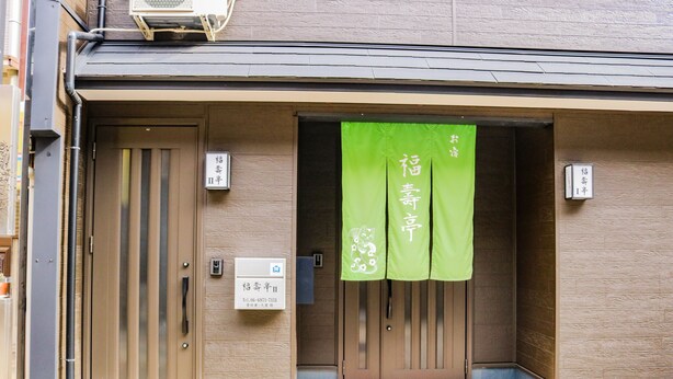 Une entrée d’immeuble avec une banderole verte, une porte et une boîte aux lettres.