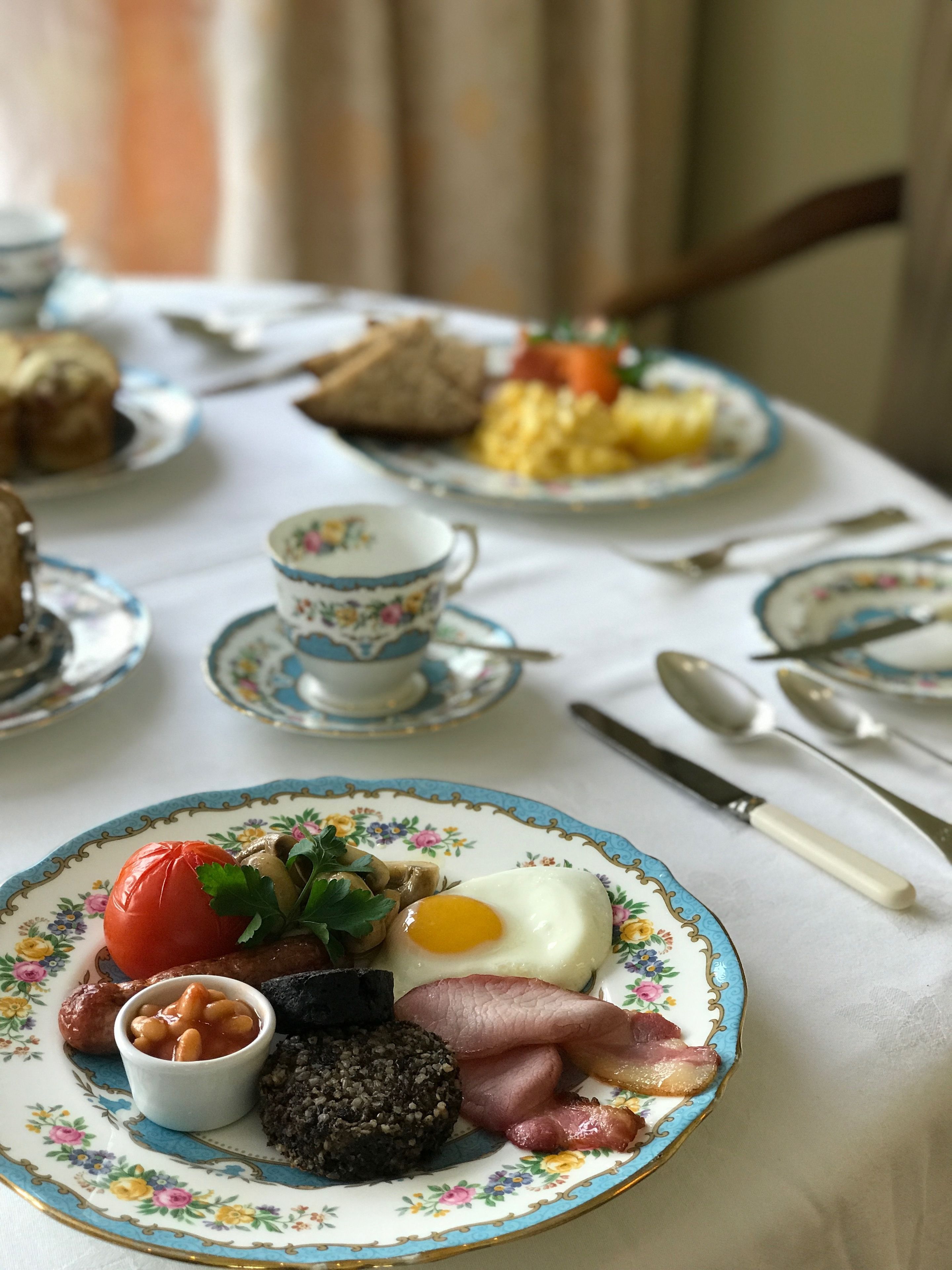 A breakfast table with plates of food, a cup, and cutlery.
