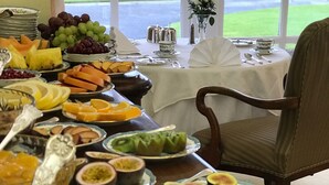A table set with various fruits and a view of a grassy area through a window. - Glenegedale House (Islay Island)