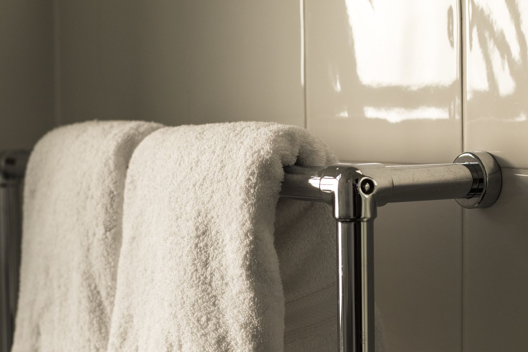 A bathroom with a towel rack holding two white towels.