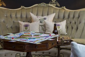 A board game set on a wooden table in front of a tufted sofa with floral cushions. - Glenegedale House (Islay Island)
