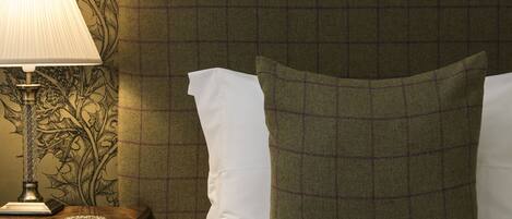 A hotel room with a bed, a nightstand with a lamp, and a wall with a floral pattern.