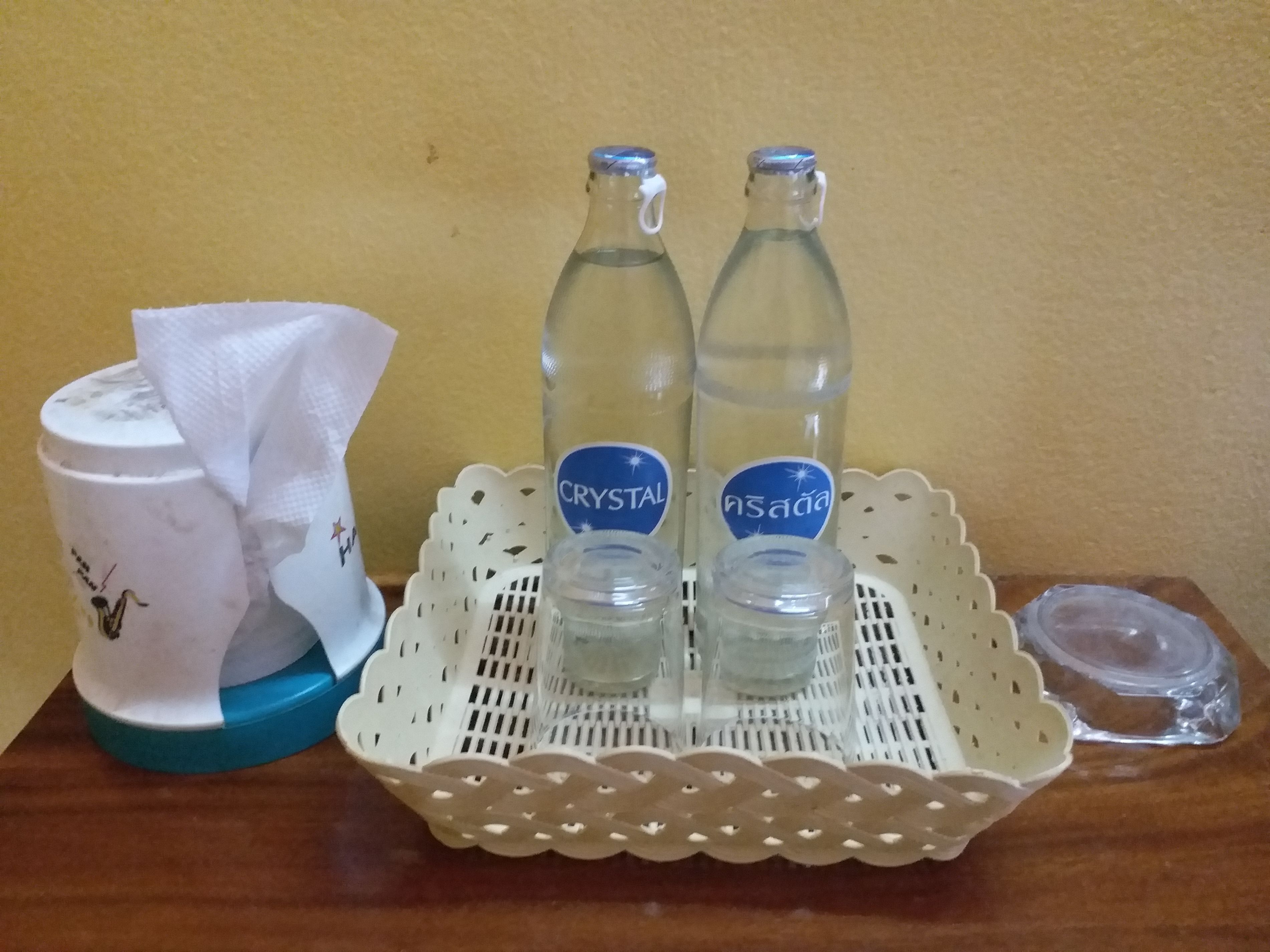 Un plateau avec deux bouteilles étiquetées « CRYSTAL » et « nsaada » est posé sur une table en bois.