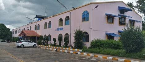 A pink building with arched windows and a sign that reads "Tuan Sudiranus."