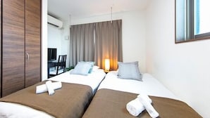 A hotel room with two beds, a desk, and a chair. - Apartment Heights HANA (Sakai)