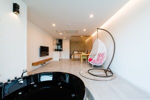 Un baño moderno con una bañera negra, un banco de madera y una silla colgante.