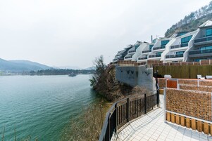 A modern building with a sloped roof, large windows, and a view of a river.