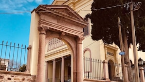 A building with a classical architectural style, featuring a central archway and a staircase leading to a door. - Kapya Cunda (Ayvalik)