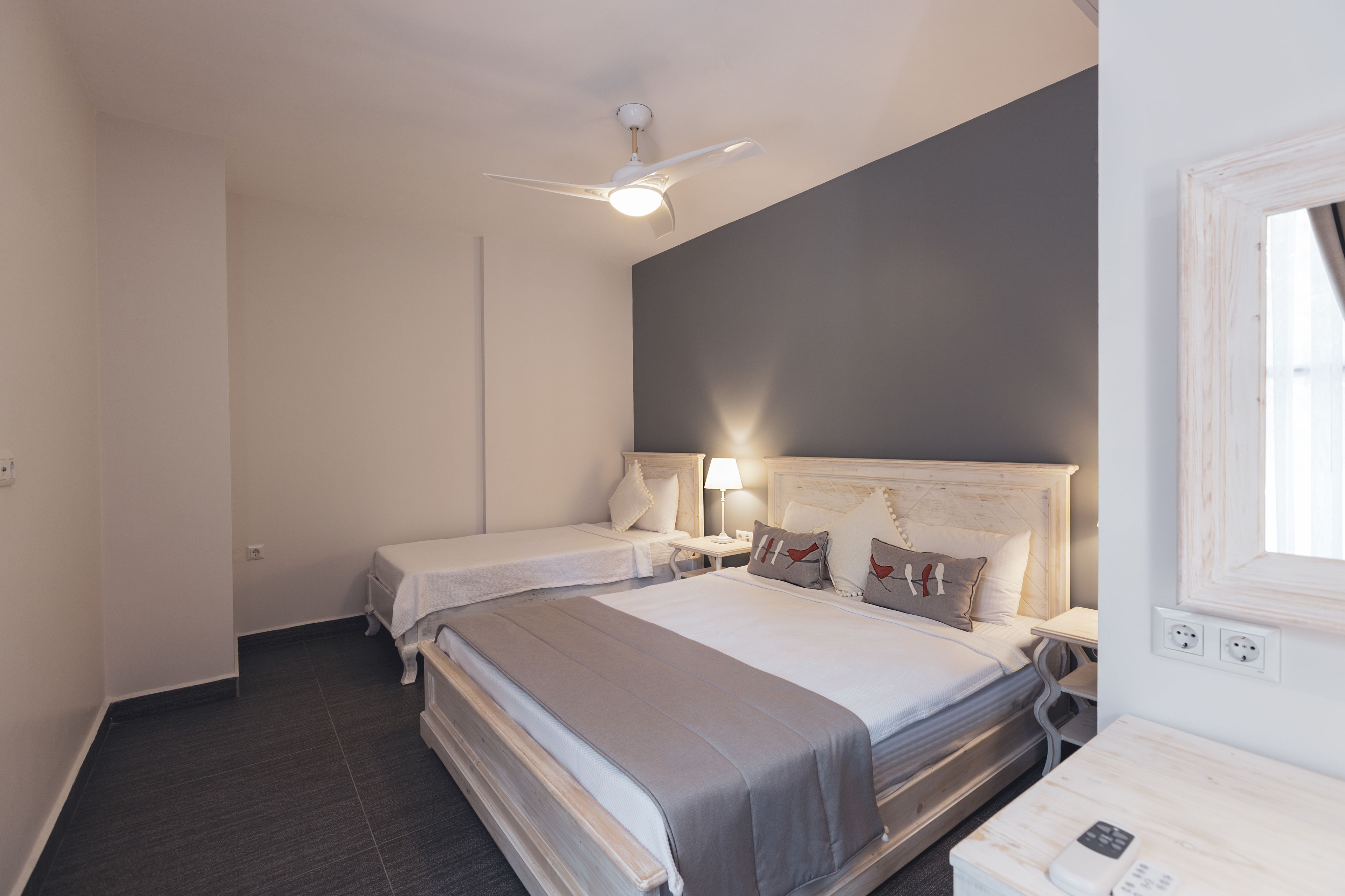 A hotel room with two beds, a ceiling fan, bedside lamps, and a bedside table with a phone.
