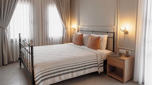 A neatly made bed with a striped bedspread, a bedside table with a lamp, and a large window with curtains. - Kapya Cunda (Ayvalik)
