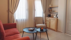 A room with a red sofa, two small tables, a chair, a bookshelf, and a door. - Kapya Cunda (Ayvalik)
