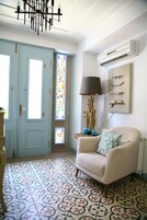 Quarto com piso estampado, porta azul clara, cadeira com almofada estampada, luminária e decoração na parede.