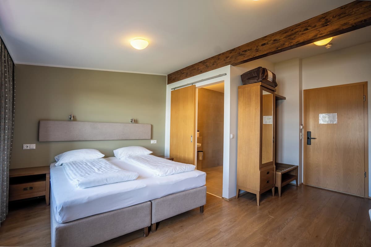 Habitación de hotel con cama, armario de madera y un banco.