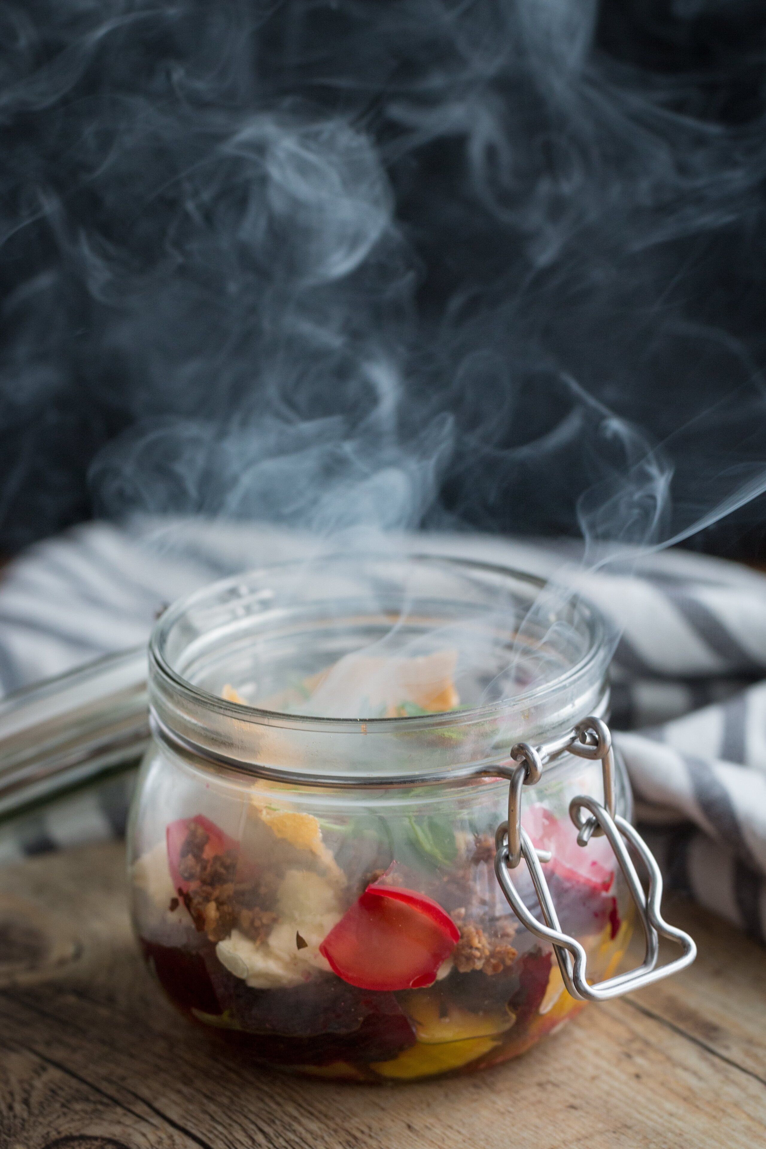 A glass jar with a metal clasp, containing various food items and emitting steam.