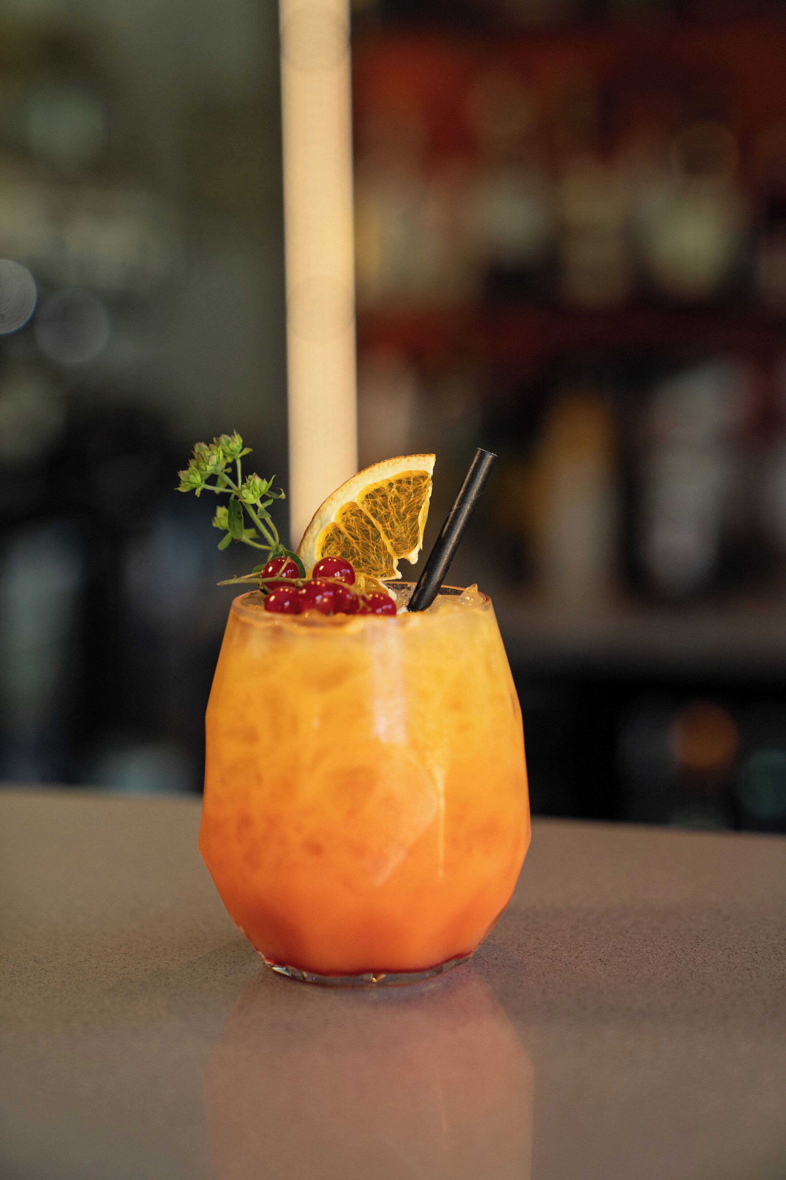 A cocktail with garnishes on a bar counter.