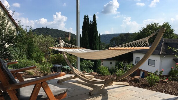 Una hamaca en un patio con vista a una casa y colinas.