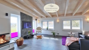 Una sala de estar moderna con una pared de piedra, una chimenea, un sillón colgante y un sofá.
