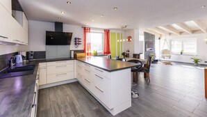 Una cocina moderna con armarios blancos, una isla central y un comedor con mesa y sillas.