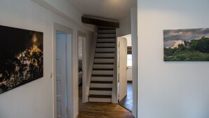 Un passadís amb una escala que condueix a una altra habitació, un quadre a la paret i una porta al final.