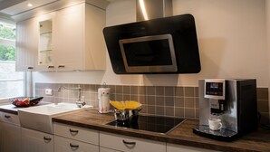 Una cuina moderna amb microones integrada, cafetera i un rentaplat.