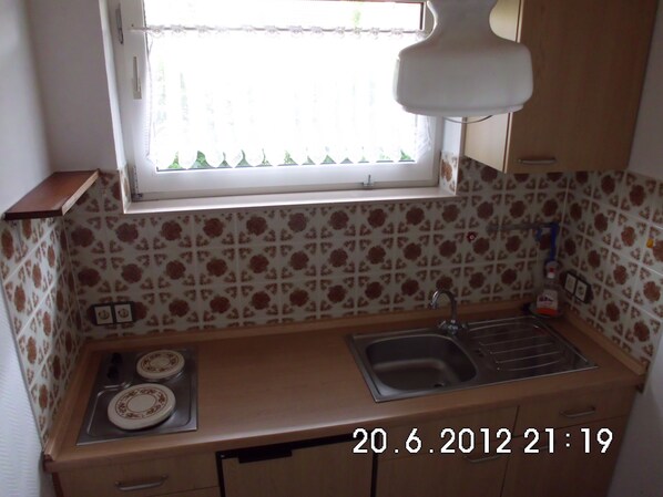 A small kitchen with a window, a sink, and a stove.