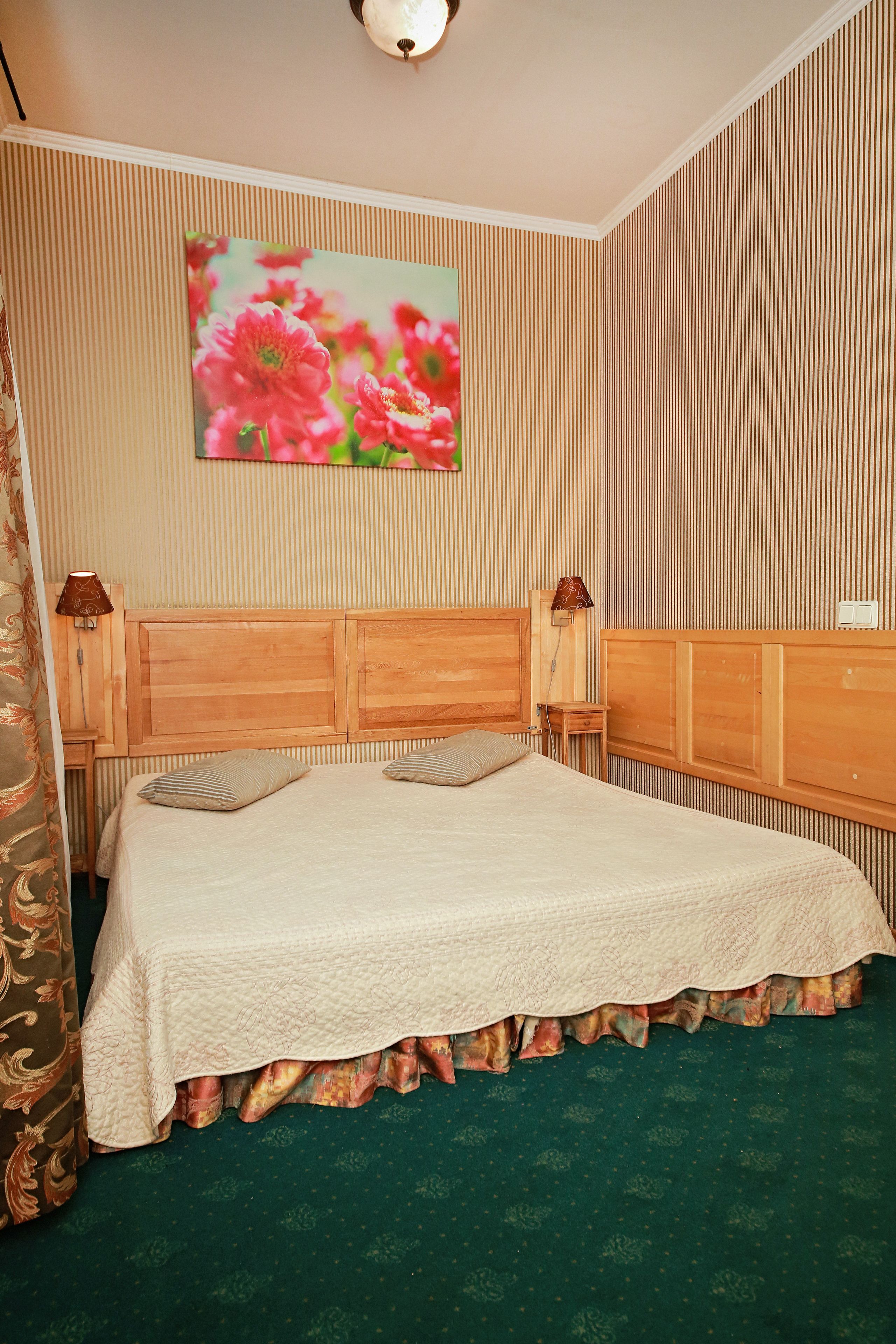 A neatly made bed with a floral headboard, a bedside lamp, and a wall-mounted light fixture.