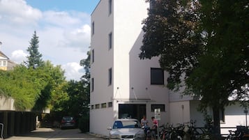A building with a white facade, a paved courtyard, and bicycles parked outside.