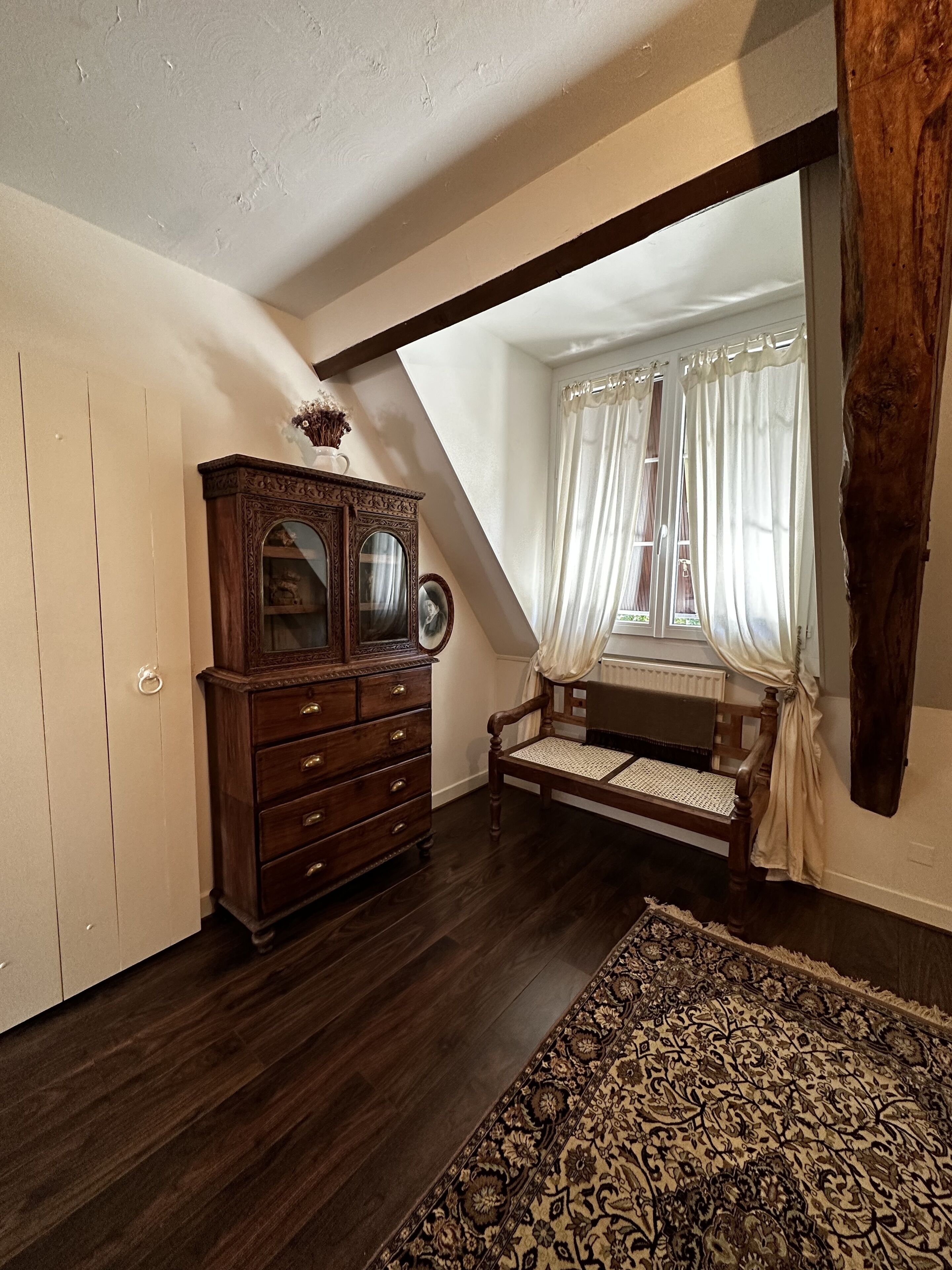 Una habitación con un aparador de madera, un banco y una alfombra estampada.