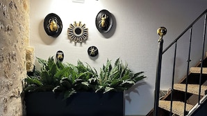 A staircase with a black railing, a wall-mounted light fixture, and a decorative sunburst mirror. - Le Vallonnet gîte (Le Vigan)
