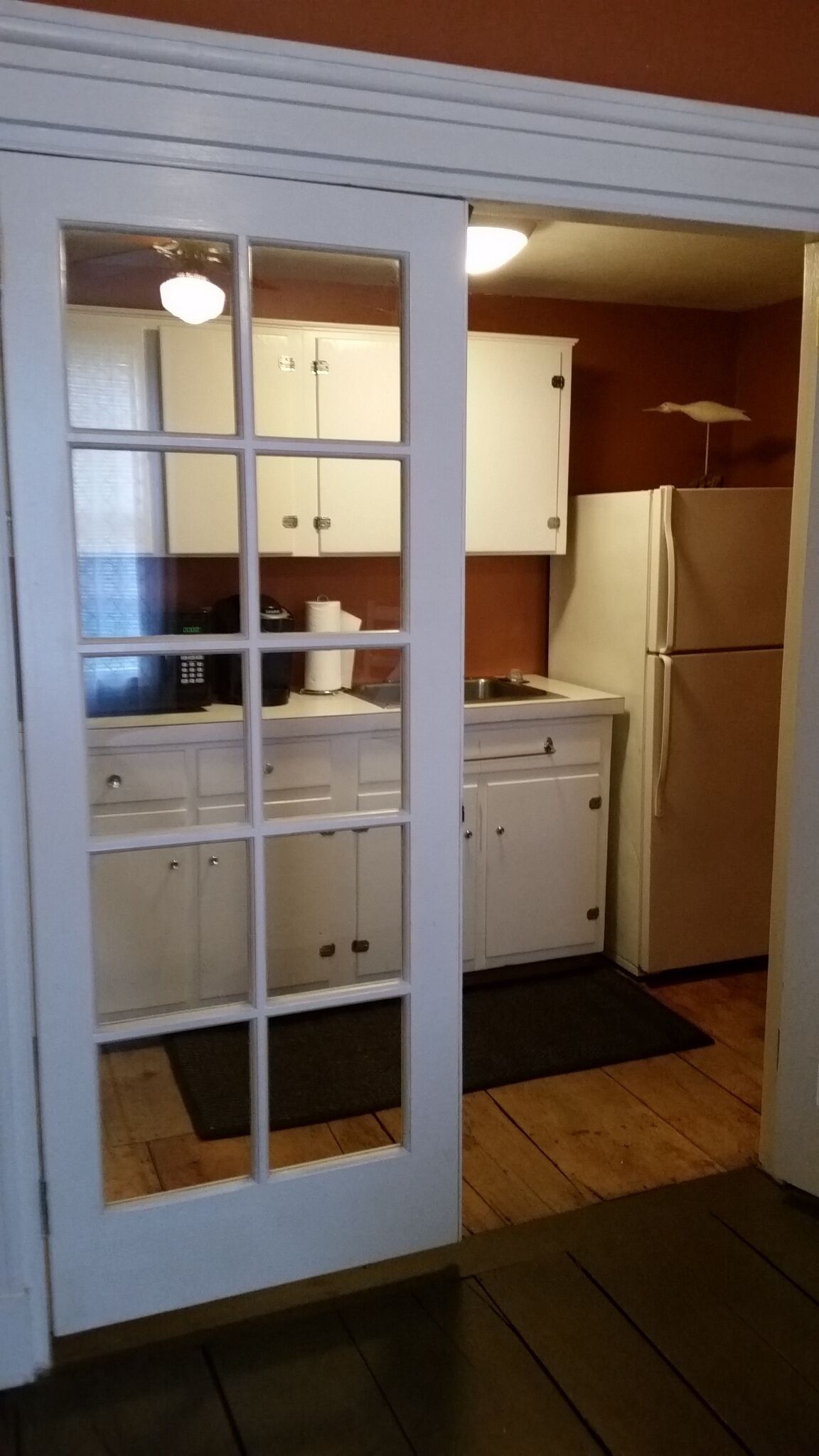 A compact kitchen with white cabinets, a refrigerator, and a microwave.