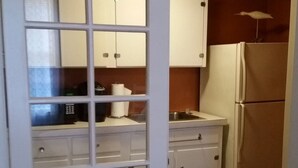 Cocina compacta con gabinetes blancos, un refrigerador y un microondas.