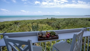 A balcony with a tray of fruits and muffins, overlooking a coastal landscape with greenery and a clear sky. - Oceanfront Key Largo Paradise - Private Beach + Pool, Hot Tub & Marina (Tavernier)