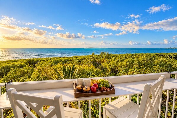 A balcony with a table set for breakfast, overlooking a lush green landscape and the sea. - Oceanfront Key Largo Paradise-Private Beach+Pool/Jacuzzi/Bar +Pickleball+Marina (Tavernier)