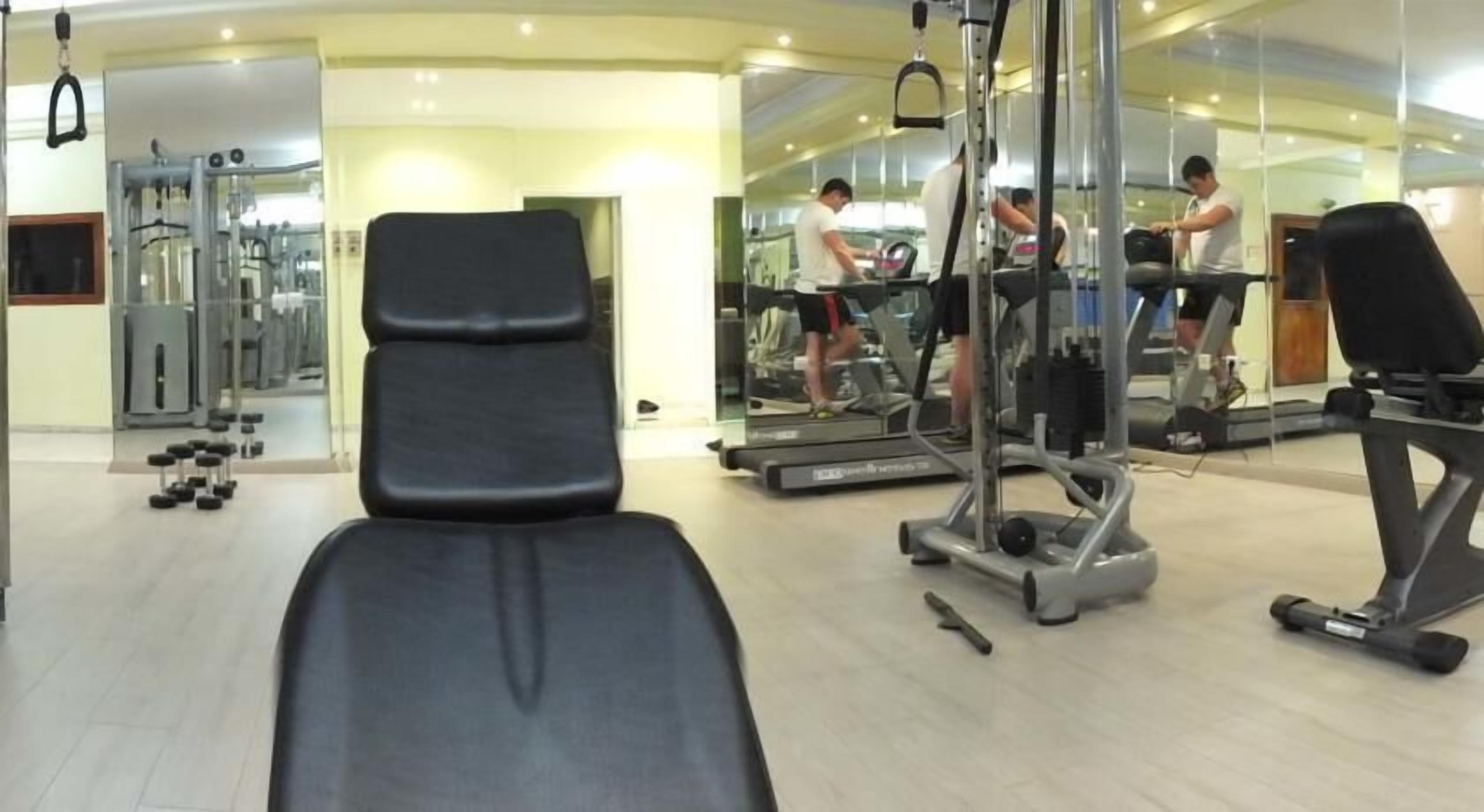 Une salle de sport équipée de matériel d’exercice, d’un banc et d’un tapis de course.