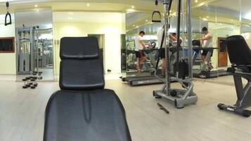 Une salle de sport équipée de matériel d’exercice, d’un banc et d’un tapis de course.