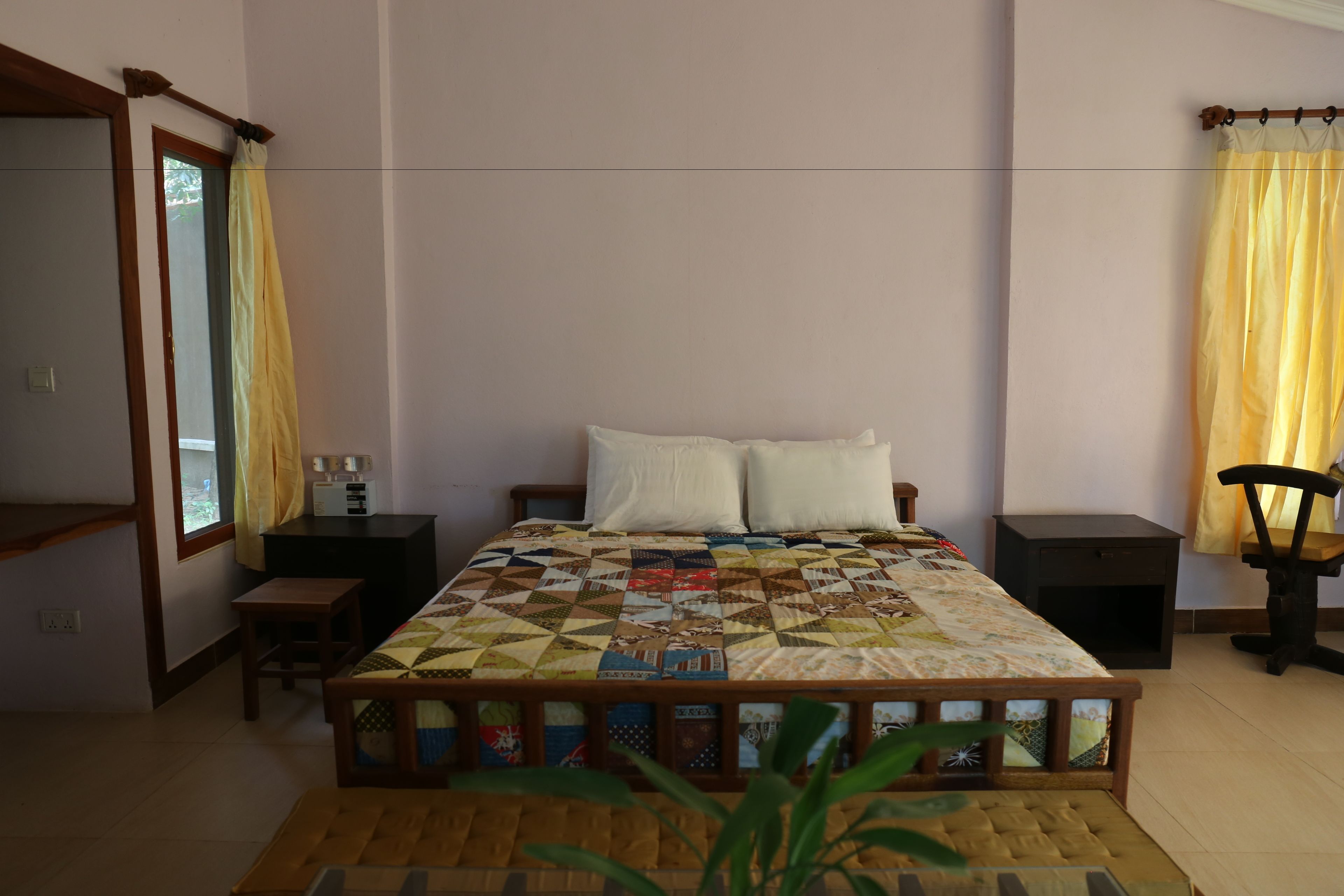 A bedroom with a bed, bedside tables, a nightstand, a mirror, and a window with curtains.