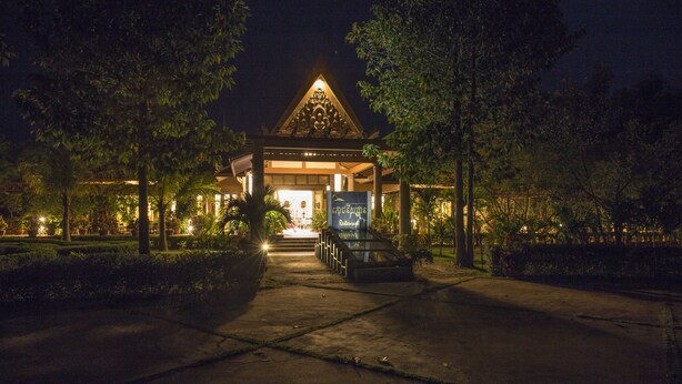 A nighttime view of a building with a triangular roof and a signboard.
